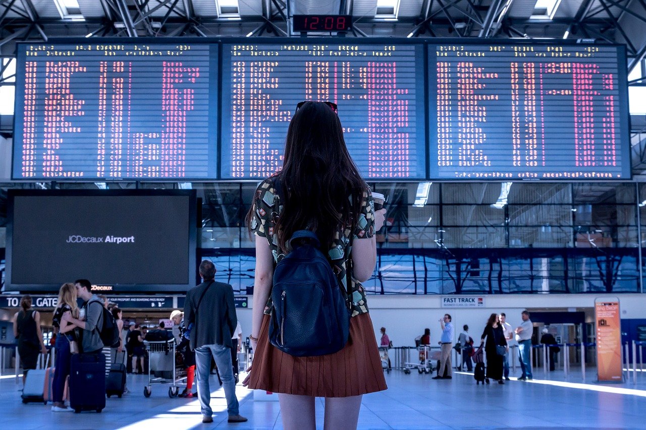 young woman looking at airport arrival and departure screens