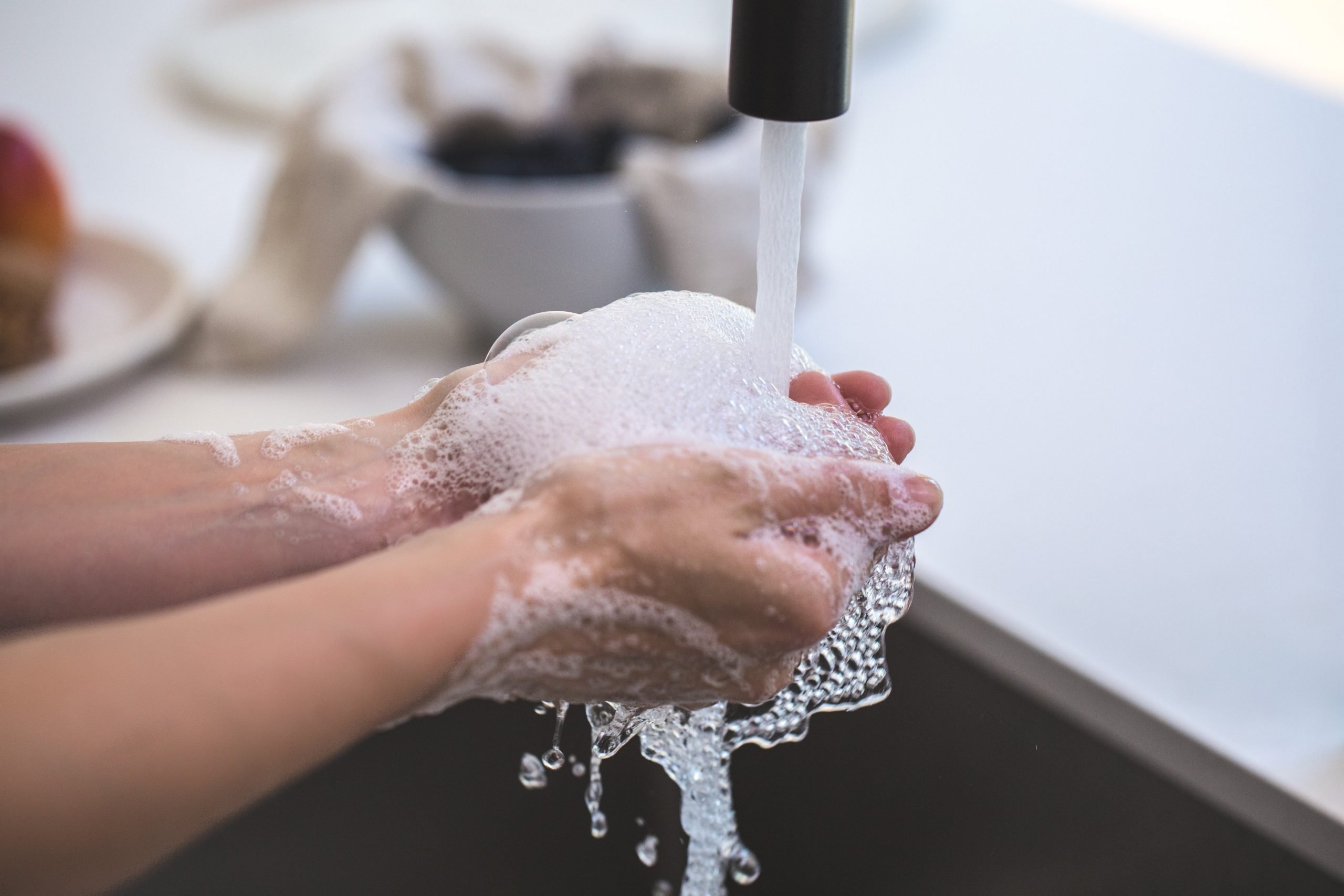 person washing their hands with soap and water to stay healthy while traveling