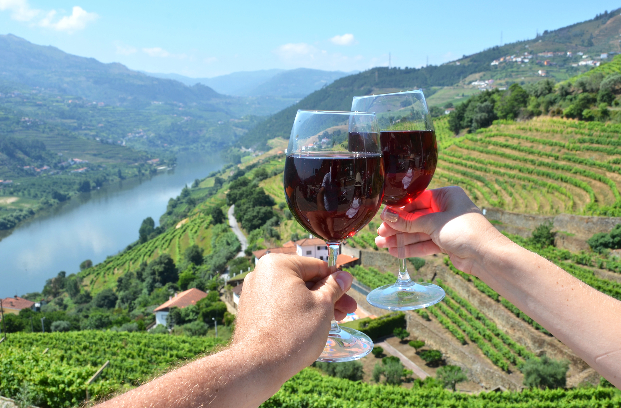 Exploring Wine Country as a Couple - Wine Glasses Toast Above Vineyard in Douro Valley Portugal