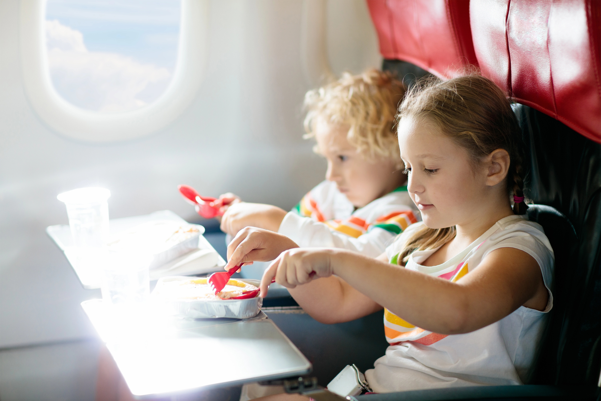 How to Entertain Kids on a Long Flight: Smart Tips for Families - Kids eating a meal on an airplane