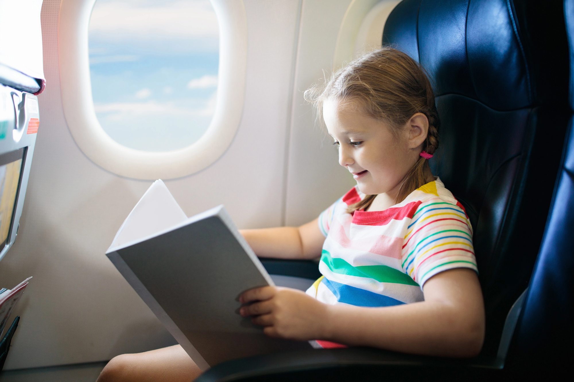 How to Entertain Kids on a Long Flight: Smart Tips for Families - Child Reading on an Airplane